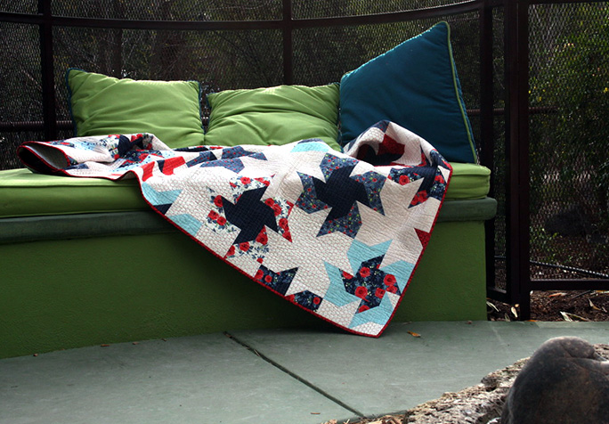 Scrappier Double Pinwheel quilt in a garden bed