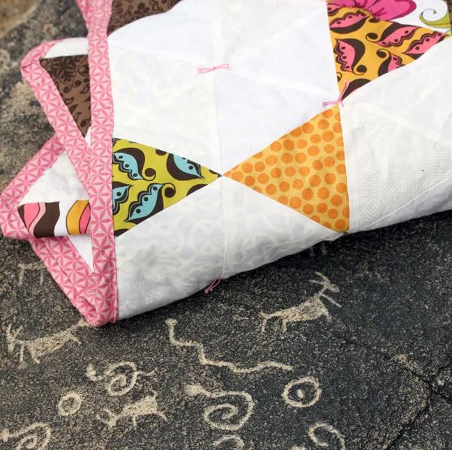 close up of the tummy time quilt on a rock with petroglifos 