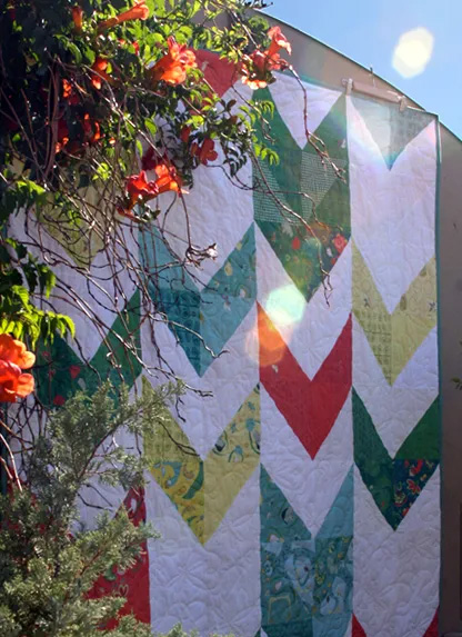 the Take Flight Quilt hanging on a garden wall