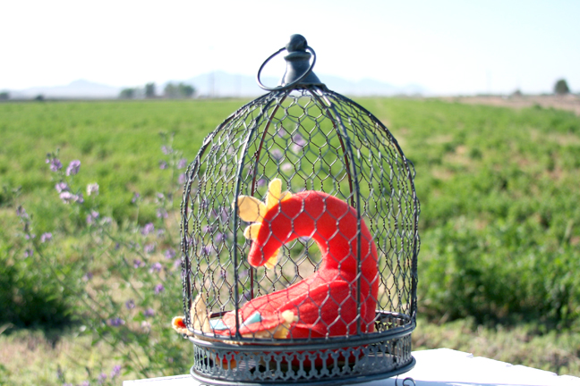 A chicken wire decorative cage for a candle with a Golden Hen Rattle inside