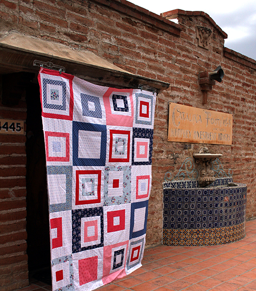 Finished quilt but not quilted hanging on a brick wall