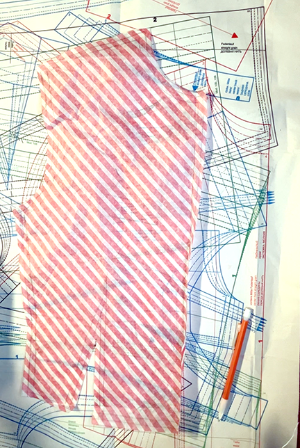 Front of the pattern for a jacket cut out using striped peppermint gift bag tissue. 